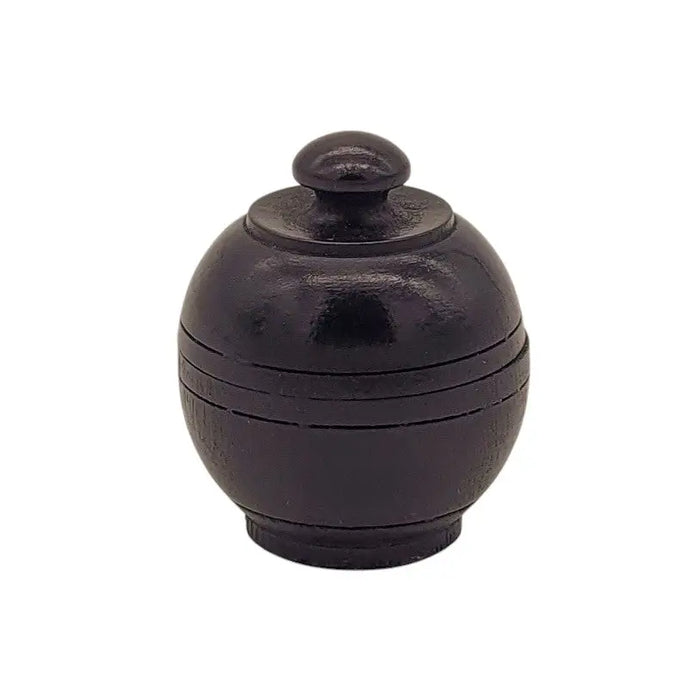 Black ceramic sugar bowl with rounded lid and ridges shown next to natural solid perfume in rosewood jar with pure beeswax