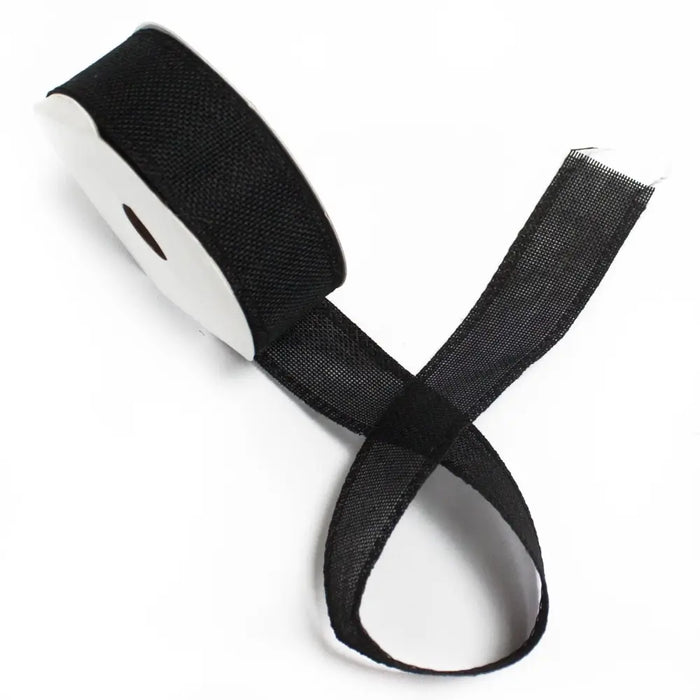 Black woven ribbon with natural texture wound on a white spool for crafting and decoration use