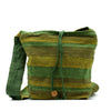 A handwoven nepal sling bag in green and olive stripes with a wooden toggle, ideal for summer beach use