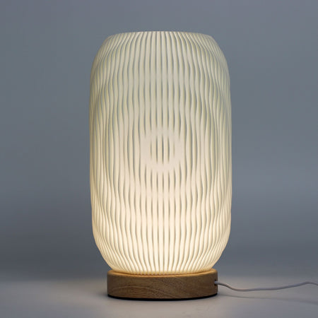 New wave lamp with a softly glowing off-white cylindrical body, vertical ridges, and wooden base for modern decor