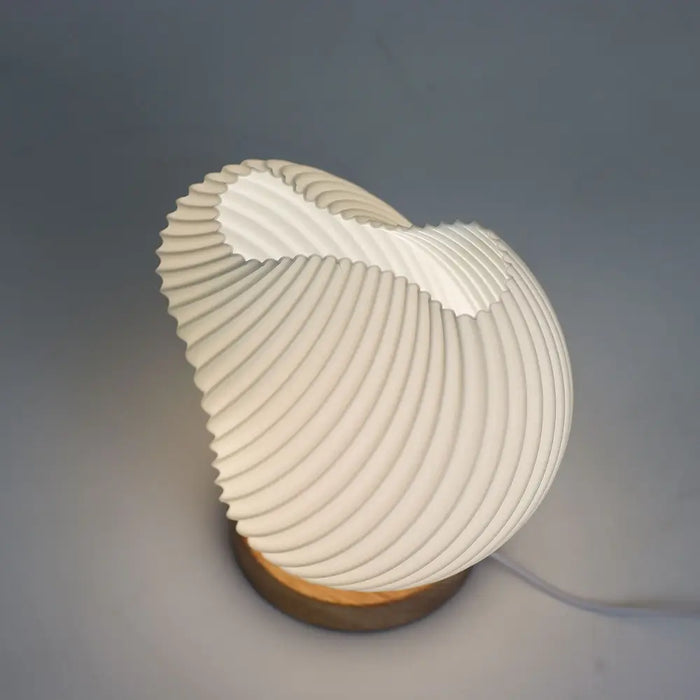 A modern white ceramic lamp with a shell twisted ribbed design and wooden base called new wave lamp shell twisted