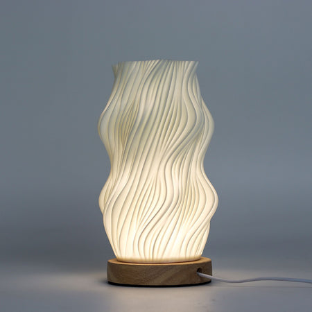 A modern cream ceramic table lamp with wavy ribbed design and wooden base called new wave lamp star twisted