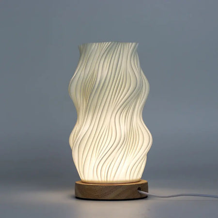 A modern cream ceramic table lamp with wavy ribbed design and wooden base called new wave lamp star twisted