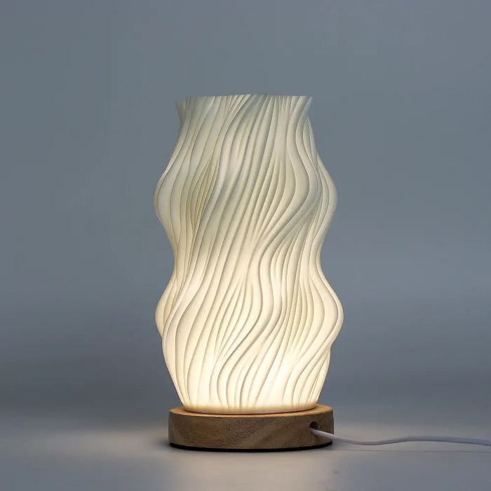 A modern cream ceramic table lamp with wavy ribbed design and wooden base called new wave lamp star twisted