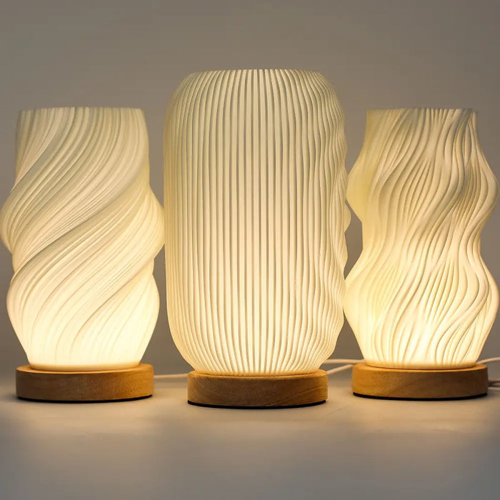 Three new wave lamps with cream textured translucent bodies and natural wood bases featuring twisted star patterns