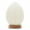 A white egg shaped wave lamp with a textured surface sits on a round wooden base called new wave lamp teardrop