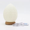 Cream-colored egg-shaped wave lamp with textured pebbled surface on a wooden base called new wave lamp teardrop