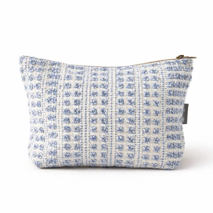 A light blue and white textured tweed toiletry bag with a gold zipper from indigo echo nomad sari collection