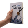 Notebook with strap featuring white cover, blue wave design, natural wood button, and we are waves in the same sea text