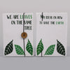 Notebook with strap showing white cover with green and black leaf designs and a wooden button closure