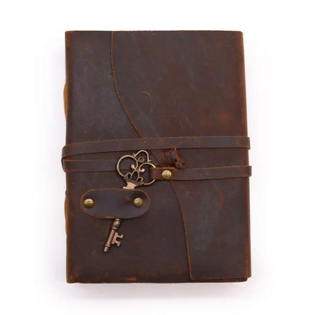Brown oiled leather journal with deckled edges and a vintage key charm attached to its strap 7 by 5 inches