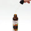 A brown glass bottle of organic hair serum with black dropper labeled castor argan infused with carrot seed 30ml