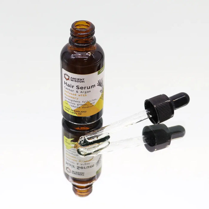 A brown glass bottle of organic hair serum with black dropper labeled castor argan infused with rosemary 30ml