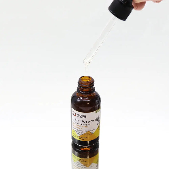A brown glass bottle of ancient wisdom organic hair serum with black dropper cap and yellow label for organic hair care