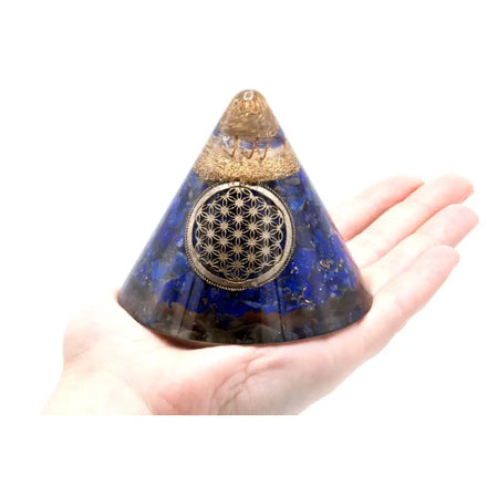A deep blue lapis lazuli resin orgonite cone with a golden copper band and silver flower of life design with suspended quartz