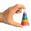 A large clear orgonite cone with multi-coloured gemstone chips layered in resin forming a rainbow energy pyramid
