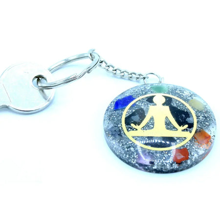 A circular orgonite power keyring with a silver metal ring and colorful gemstone resin featuring a golden buddha silhouette