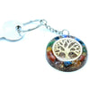 A circular orgonite power keyring with a golden tree of life and colorful gemstones in clear resin