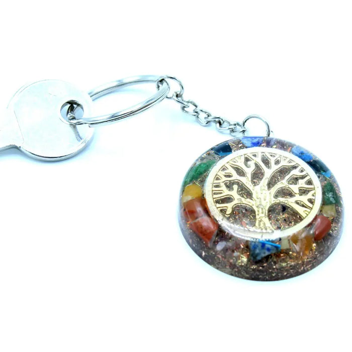 A circular orgonite power keyring with a golden tree of life and colorful gemstones in clear resin