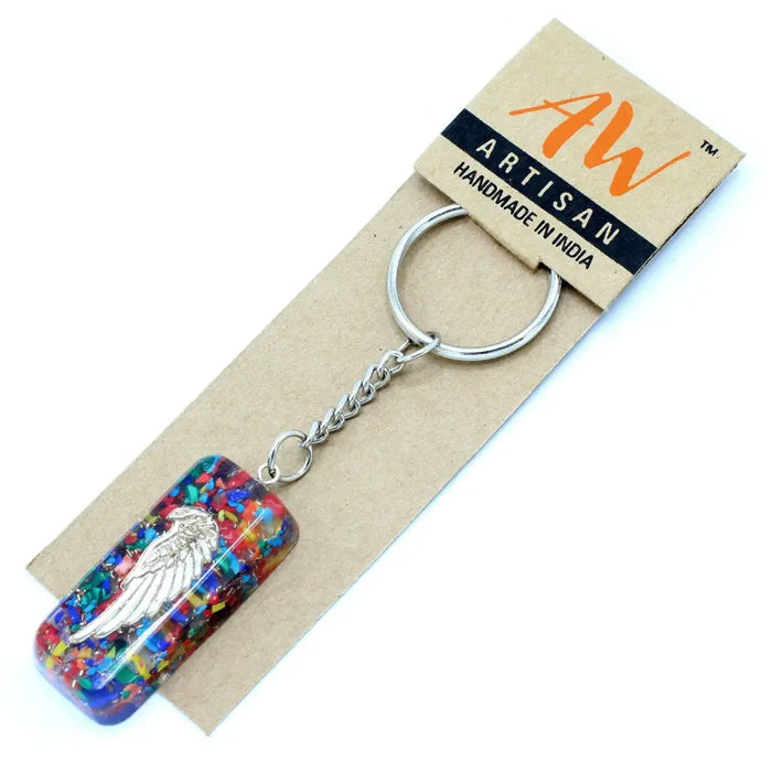 A rectangular translucent orgonite power keyring with colorful resin, multicolored glitter, and silver angel wings inside