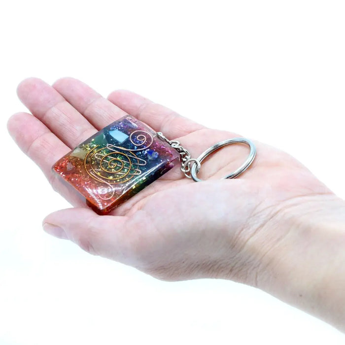 A colorful rectangular resin orgonite power keyring with embedded gemstones and gold spiral designs for home protection