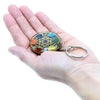 A round orgonite power keyring with a gold geometric design and rainbow gemstones in a chakra pattern
