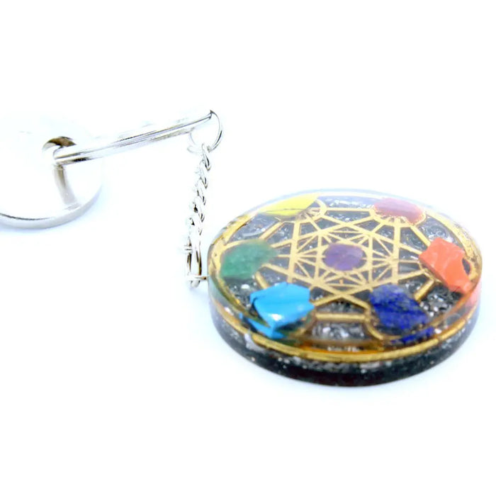 Orgonite power keyring round with embedded colorful gemstones in clear resin and golden geometric design on dark base