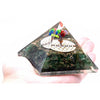 A clear resin orgonite pyramid with green aventurine, gold flecks, colorful beads, and a white flower of life design