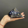 A sleek black resin orgonite pyramid with golden flecks and colorful mystical symbols on its face