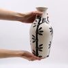 A white ceramic vase with a black bamboo leaf pattern in a natural ornamental shaped design