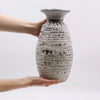 Ornamental shaped ceramic vase cream with textured gray surface and raised circular bands and flared rim