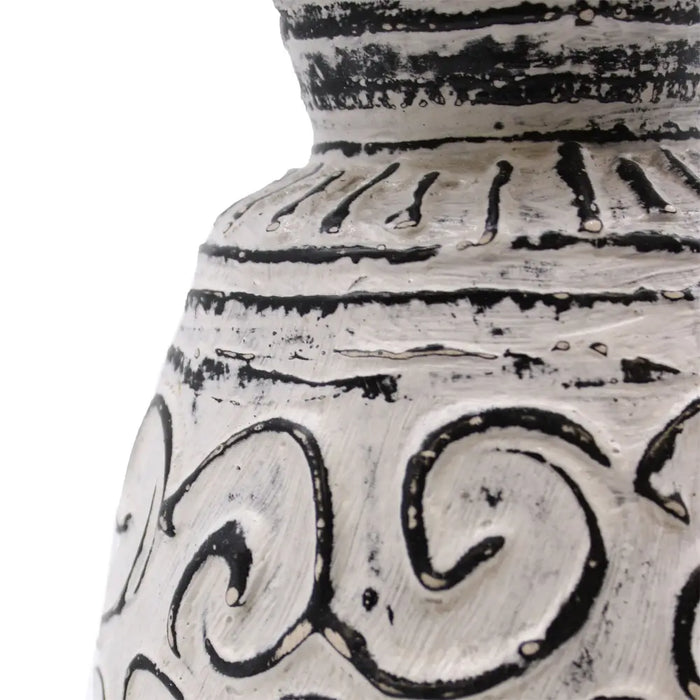A white ceramic ornamental vase with black hand-painted swirling and linear patterns in a cream setting