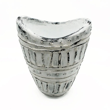 A distressed silver-toned ceramic vase with a wide neck, curved top, vertical ridges, and circular studs in cream tones