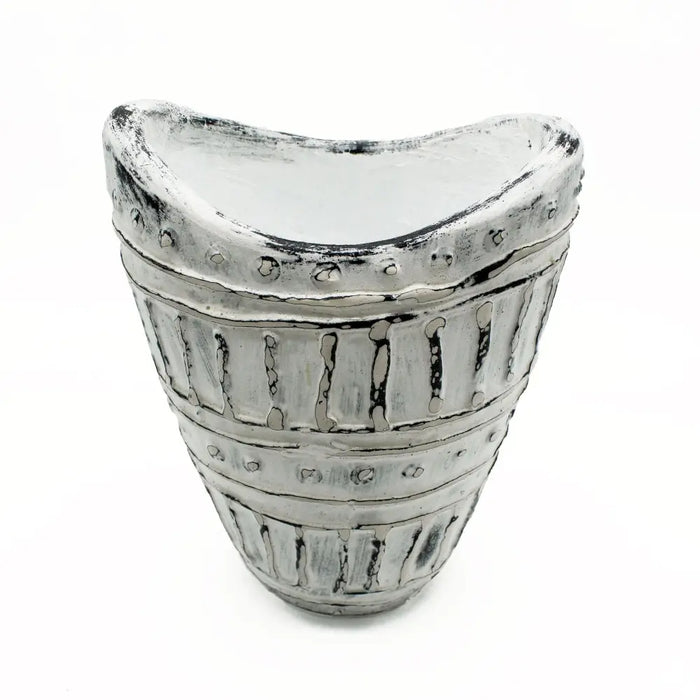 A distressed silver-toned ceramic vase with a wide neck, curved top, vertical ridges, and circular studs in cream tones