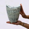Ornamental shaped ceramic vase in cream with a wide neck textured with raised vertical ridges and circular indentations