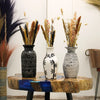 Three ornamental straight ceramic vases in black white and gray with greek patterns on a rustic wooden table