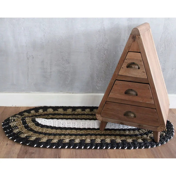 Triangular wooden dresser with three drawers and brass handles on a natural black and white oval-shaped seagrass rug