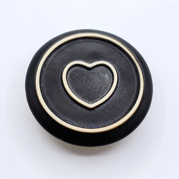 Black ceramic smudge holder with raised gold heart design for palo santo sticks and sage bundles use