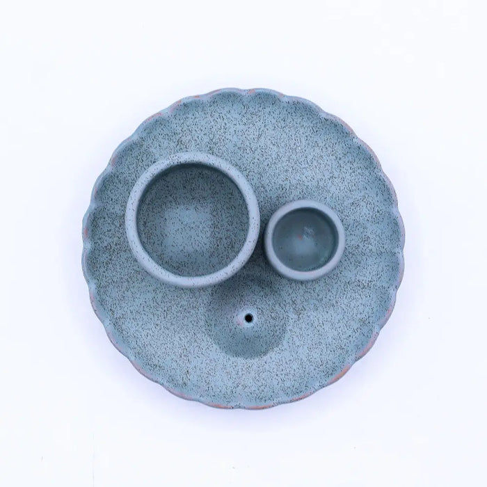 A blue speckled teal ceramic palo santo stick and smudge holder with scalloped edges and two circular bowls