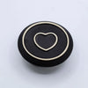 Black circular palo santo stick and smudge holder with cream heart outline and mandala ring detail in white and grey