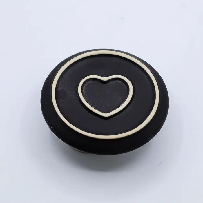 Black circular palo santo stick and smudge holder with cream heart outline and mandala ring detail in white and grey