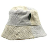 A natural-toned cotton boho festival bucket hat with patched hemp fabric and a subtle woven pattern with a brand tag