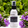A sleek silver essential oil spray bottle with black pump labeled ancient wisdom aromatherapy mist patchouli essential oil