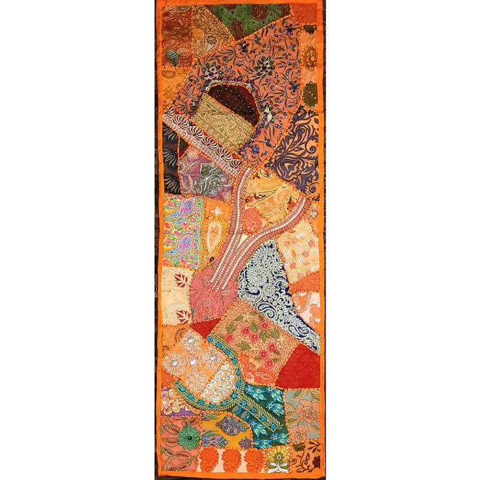A patchwork wall hanging and table runner in orange red blue and green fabrics with floral and paisley patterns
