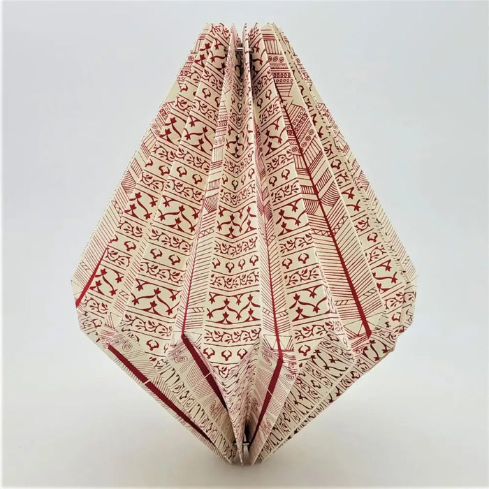 A cream paper geometric origami light shade with red tribal patterns designed as a short pendant light shade
