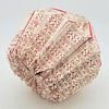 A cream-colored paper short pendant origami light shade with red geometric tribal-inspired patterns folded complexly