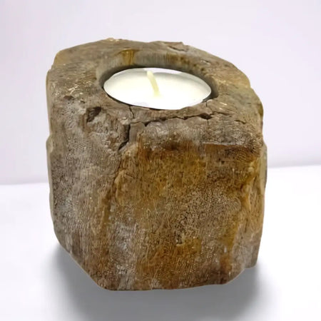 Rough textured earthy toned petrified wood tealight holder with circular cutout holding a white tea light candle
