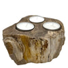 A rustic petrified wood tealight holder with three circular indentations holding white tea light candles