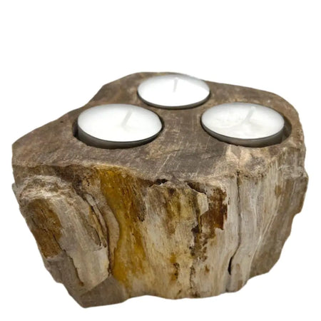 A rustic petrified wood tealight holder with three circular indentations holding white tea light candles