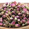 A wooden bowl filled with dried pink rose buds showing purple and green hues weighing 0.5kg